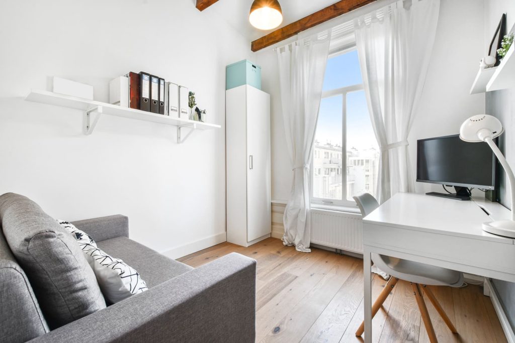 Portrait of a small room image shot into a corner to visually extend it as one of the tips for Airbnb photos.